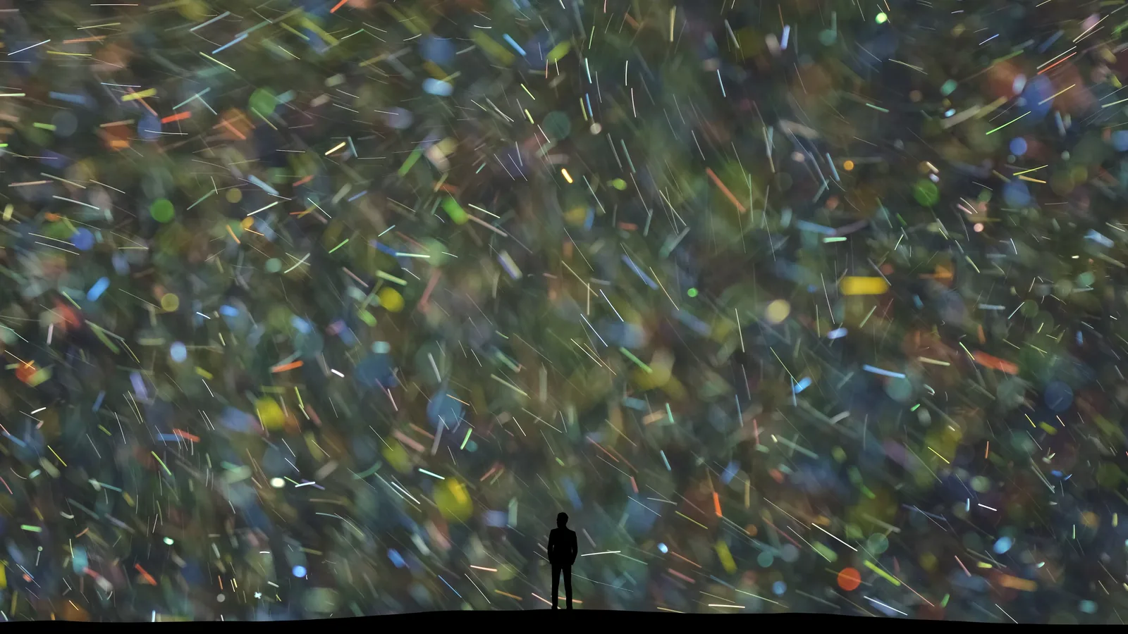 A lone figure silhouetted against a vast wall of shifting colored light.